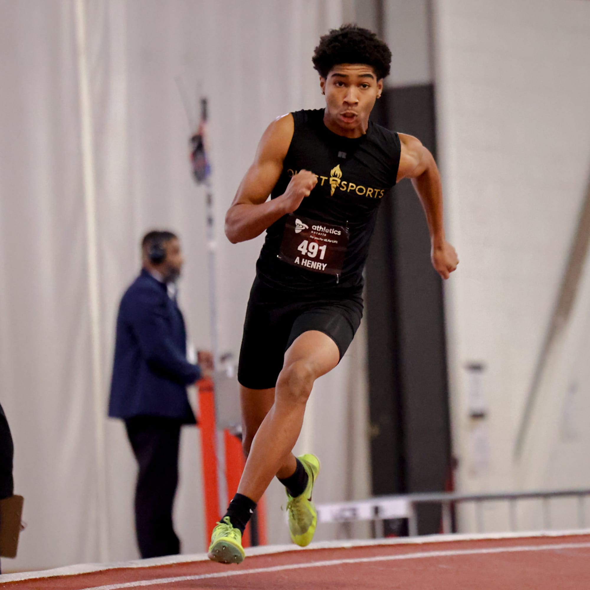Quest Sports sprinter in black kit racing on an indoor track
