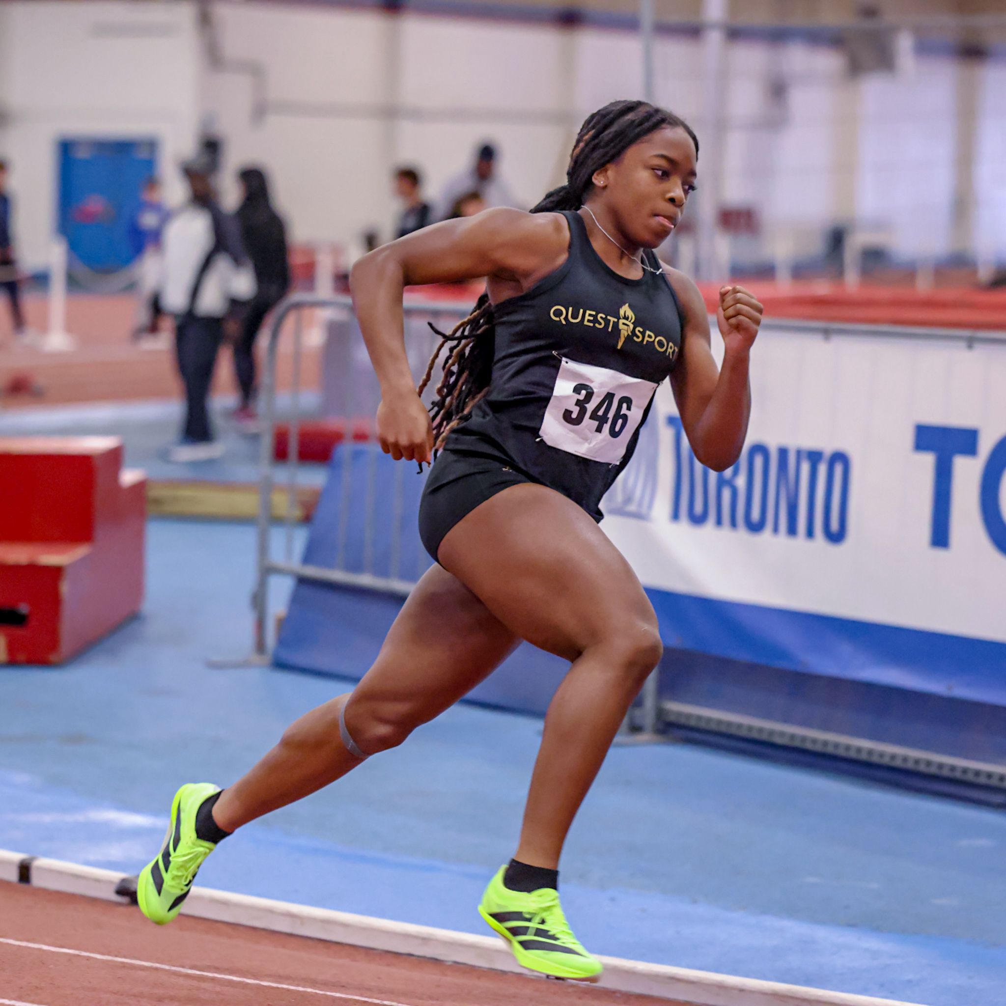 Quest Sports sprinter in black kit racing at a Toronto indoor meet